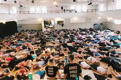Dozens of people lay on the floor in a dance studio, participating in Dance Church